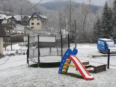 a playground with a slide in the snow at Noclegi w gorcach in Ponice