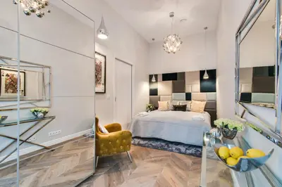 a bedroom with a bed and a chair and a mirror at Kings City - Zyblikiewicza 14 apartment in Kraków