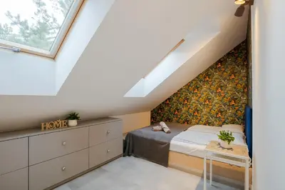 a attic bedroom with a bed and a window at Słoneczny Chełm - Apartamenty w górach, Prywatna sauna jacuzzi balia w cenie, Spa, Grill, Stok narciarski Myślenice, Ścieżki rowerowe, Rzeka Raba, Widok na Tatry in Myślenice