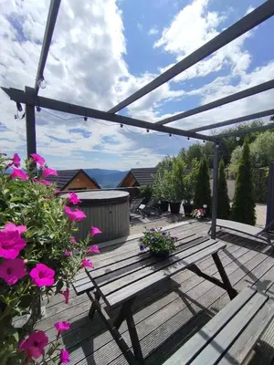 a wooden bench sitting on a deck with flowers at Słoneczny Chełm - Apartamenty w górach, Prywatna sauna jacuzzi balia w cenie, Spa, Grill, Stok narciarski Myślenice, Ścieżki rowerowe, Rzeka Raba, Widok na Tatry in Myślenice