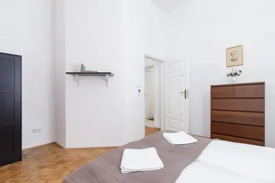 a white bedroom with a bed and a dresser at Apartment Pijarska Kraków by Noclegi Renters in Kraków