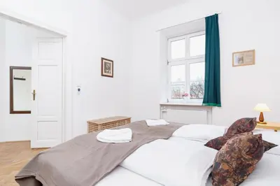 a white bedroom with a large bed and a window at Apartment Pijarska Kraków by Noclegi Renters in Kraków