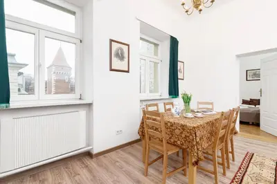 a dining room with a table and chairs and windows at Apartment Pijarska Kraków by Noclegi Renters in Kraków