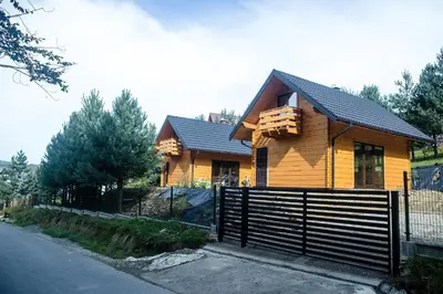 a wooden house with a fence in front of it at Domki na Mosornym in Zawoja