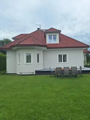 a white house with chairs in a yard at Villa pod Szczeblem Dom dla 12 osób z kominkiem balią jacuzzi in Kasinka Mala