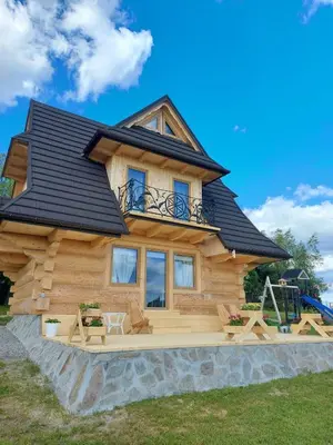 a log cabin with a deck and a house at Dom na Wichrowym Wzgórzu in Łętownia Dolna