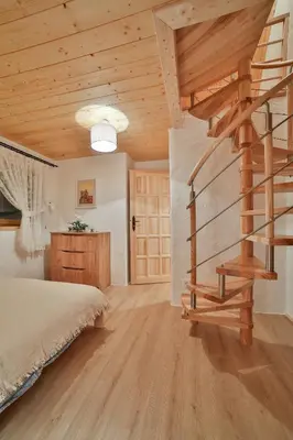 a bedroom with a bed and a spiral staircase at Dom na Wichrowym Wzgórzu in Łętownia Dolna