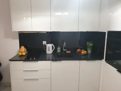 a kitchen with white cabinets and a black counter top at Lovely Apartment near Wawel in Kraków