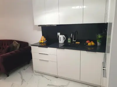 a kitchen with white cabinets and a black counter top at Lovely Apartment near Wawel in Kraków