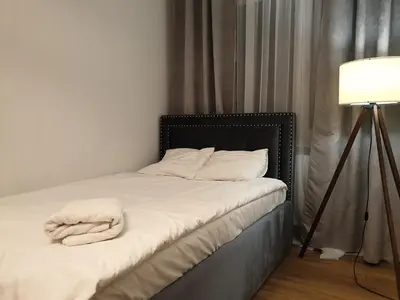 a bedroom with a bed with white sheets and a lamp at Lovely Apartment near Wawel in Kraków