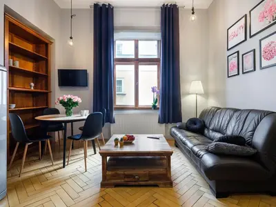 a living room with a leather couch and a table at CracWoW Market Squere Apartment in Kraków