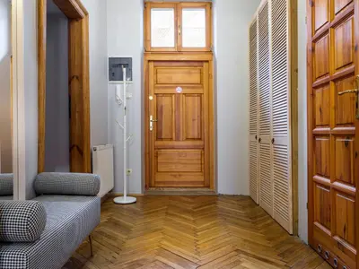 a room with a wooden door and a couch in front at CracWoW Market Squere Apartment in Kraków