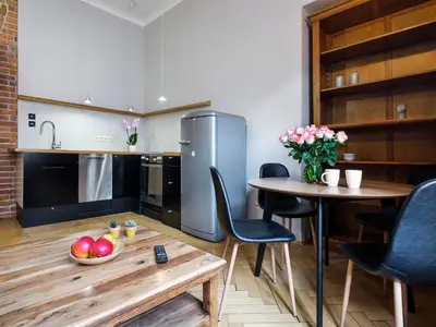 a kitchen with a table and chairs and a refrigerator at CracWoW Market Squere Apartment in Kraków