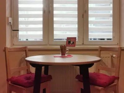 a table and two chairs with a table and two windows at Little Big Red - Central Modern Studio in Kraków