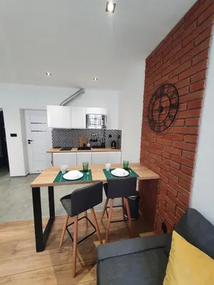 a kitchen with a table and chairs and a brick wall at Mirror Apartments in Oświęcim