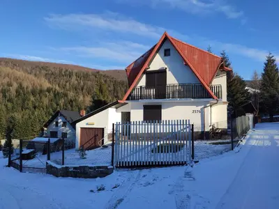 a white house with an orange roof in the snow at Domek Zawoja in Zawoja