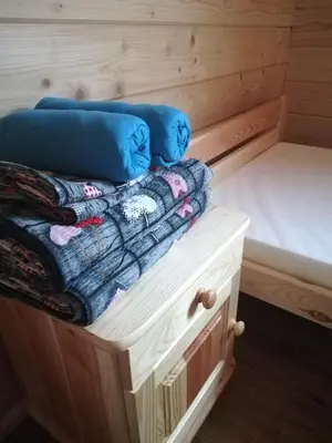 a bed and pillows sitting on top of a wooden cabin at Słoneczne Chaty Kasina Wielka in Kasina Wielka