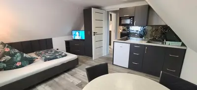 a living room with a couch and a kitchen at Pokoje Gościnne Tyrol in Zawoja
