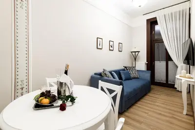 a living room with a white table and a blue couch at Apart Residence Ariańska 16 by NEARTO PL in Kraków