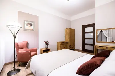 a bedroom with a white bed and a chair at Apart Residence Ariańska 16 by NEARTO PL in Kraków