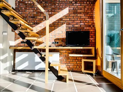 a room with a desk with a television and a brick wall at Zwierzyniecka Lofts with Patio and Air Conditioning, Cracow city heart Old Town in Kraków