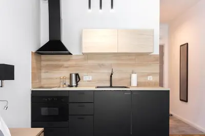 a kitchen with black cabinets and a white wall at Old Town Rajska street in Kraków