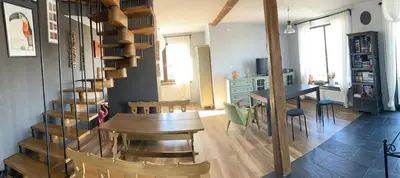 a living room with a wooden table and a spiral staircase at Chata na Łąkach in Jerzmanowice