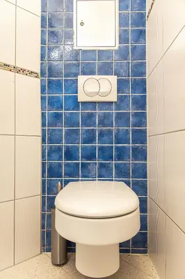 a blue tiled bathroom with a toilet in it at Mateyko Boho in Kraków