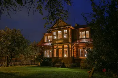 a large wooden building with two people in the doorway at Willa Dalia in Rabka