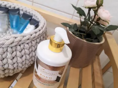 a bottle of moisturizers next to a vase of flowers at ZamStudio Kraków Zamenhofa 4 in Kraków