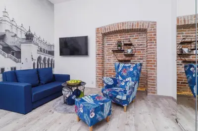 a living room with a blue couch and two chairs at ZamStudio Kraków Zamenhofa 4 in Kraków