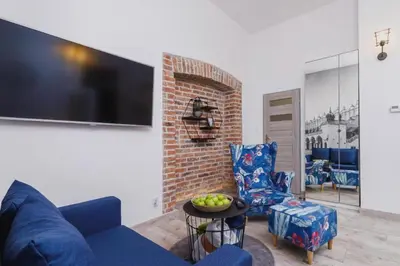 a living room with a blue couch and a tv at ZamStudio Kraków Zamenhofa 4 in Kraków