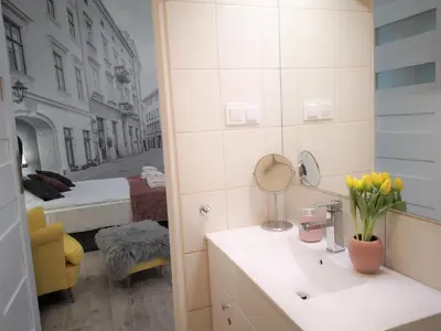 a bathroom with a sink and a bedroom with a bed at ZamStudio Kraków Zamenhofa 4 in Kraków
