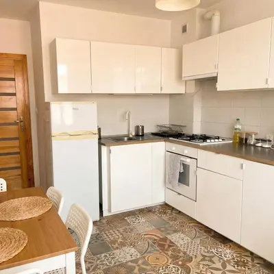 a kitchen with white cabinets and a wooden table at Beautiful apartment with balcony in Kraków