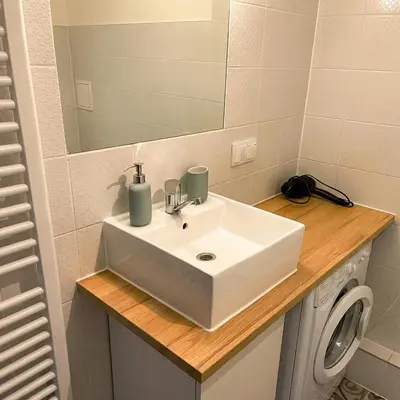 a bathroom sink with a mirror and a washing machine at Beautiful apartment with balcony in Kraków