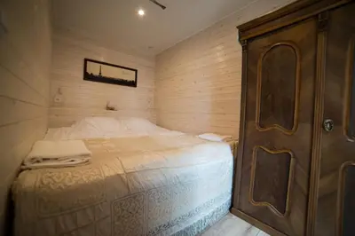 a small bedroom with a bed and a wooden wall at JURA GLAMP luksusowe całoroczne domki na wyłączność KOPUŁY IGLOO taras ogród in Wola Kalinowska