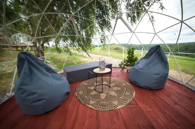 a table and two pillows on a wooden deck at JURA GLAMP luksusowe całoroczne domki na wyłączność KOPUŁY IGLOO taras ogród in Wola Kalinowska