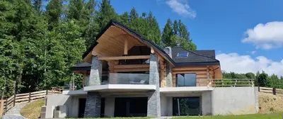 a house built on top of a hill with trees at Domki PRemium in Zawoja