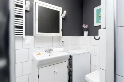 a white bathroom with a sink and a mirror at Premium Apartment Ludwinowska Kraków by Noclegi Renters in Kraków
