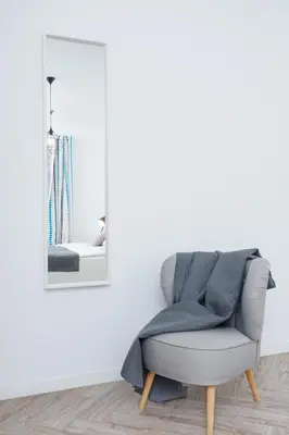 a grey chair in a white room with a mirror at Premium Apartment Ludwinowska Kraków by Noclegi Renters in Kraków