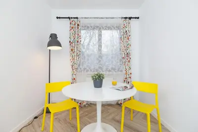 a dining room with yellow chairs and a white table at Premium Apartment Ludwinowska Kraków by Noclegi Renters in Kraków