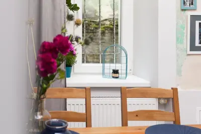 a table with a vase of flowers and a window at Quiet & Comfortable Old Krakow Apartment in Kraków