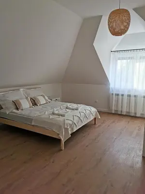 a white bedroom with a bed and a wooden floor at Hygge House in Zator