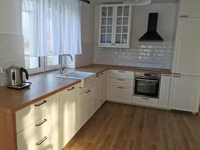 a kitchen with white cabinets and a wooden floor at Hygge House in Zator