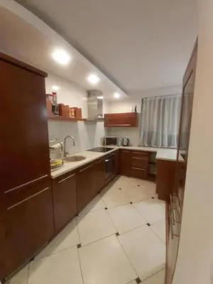 a large kitchen with wooden cabinets and a tile floor at APARTAMENT LUCYNA in Rabka