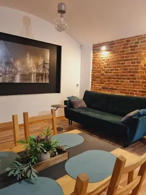 a living room with a couch and a brick wall at Apartament pod Wawelem in Kraków