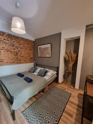 a bedroom with a bed and a brick wall at Apartament pod Wawelem in Kraków