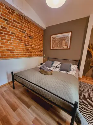 a bed in a room with a brick wall at Apartament pod Wawelem in Kraków