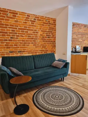 a living room with a green couch and a brick wall at Apartament pod Wawelem in Kraków