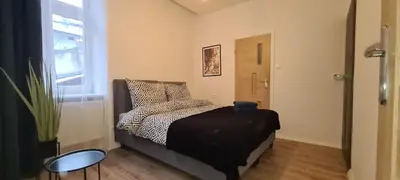 a bedroom with a bed and a table and a window at Paderewskiego Old Town Apartaments in Kraków